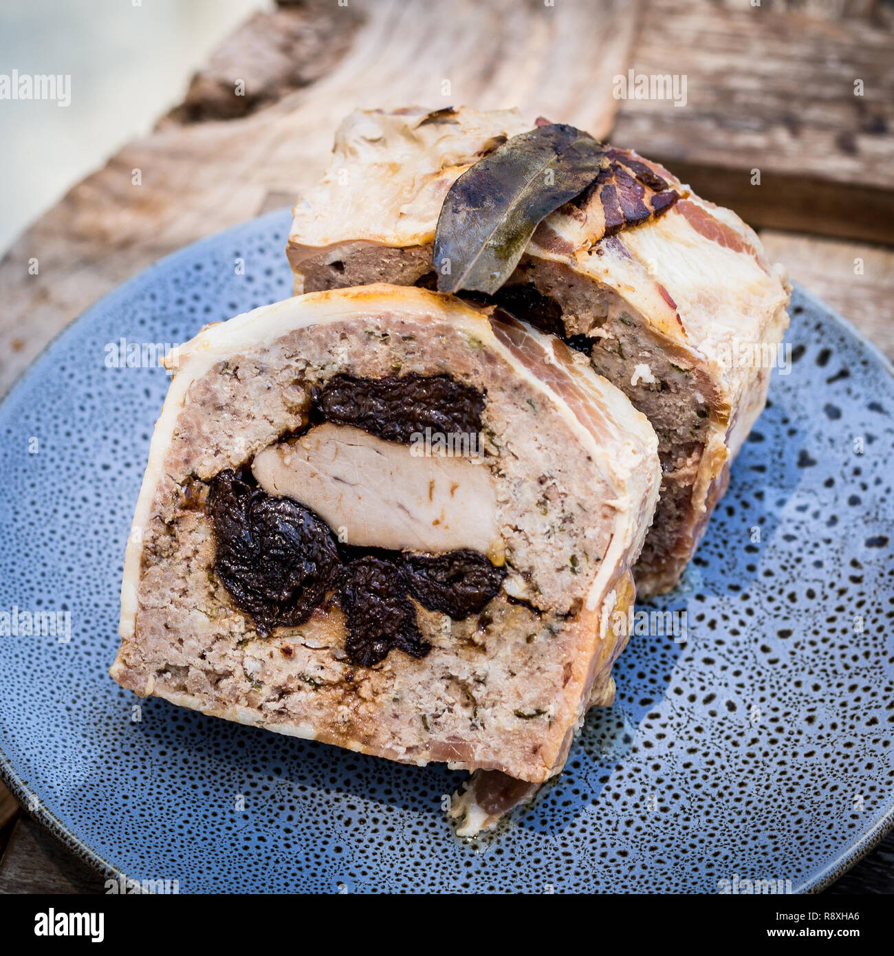 Terrina de cerdo y ciruelas sobre placa azul en palet de madera en picnic Foto de stock