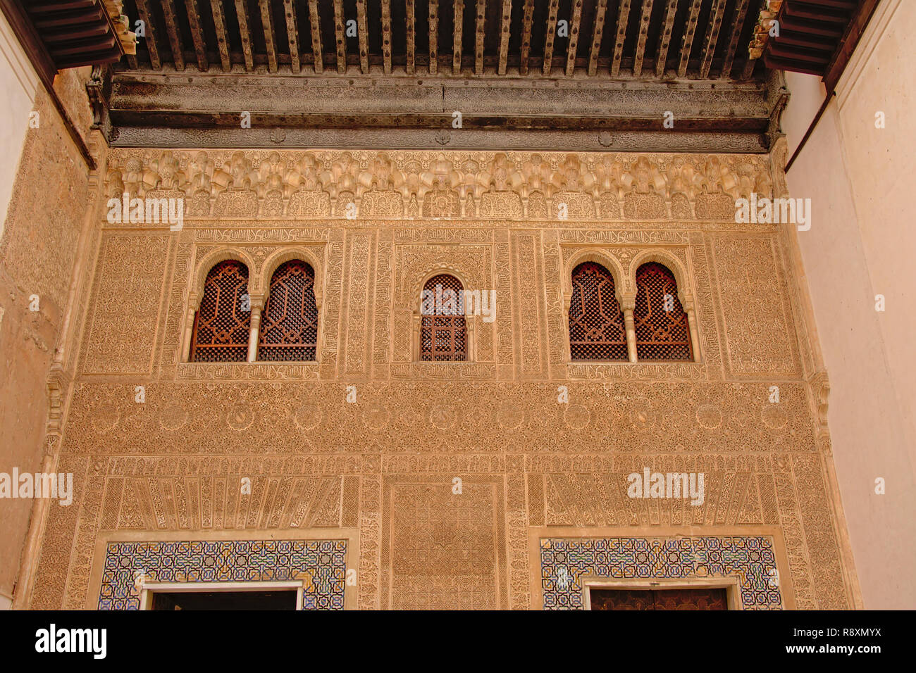 Pared con elaborar patrones decorativos y caligraphy orgánicos y ventanas con estrellas y otras formas, detalle del palacio nazarí , Alhambra, España Foto de stock