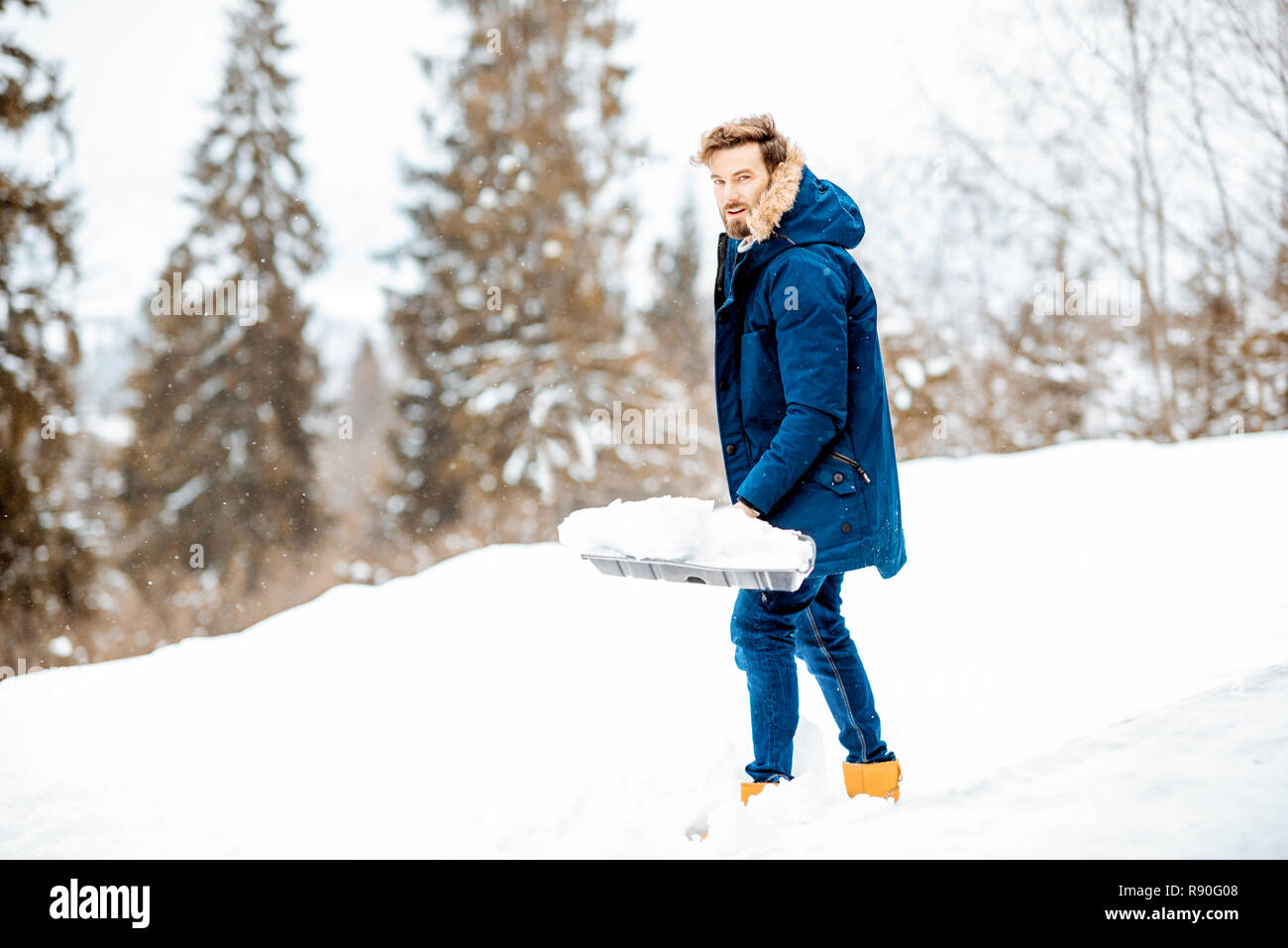 Hombre en ropa de invierno de limpieza con una pala de nieve en