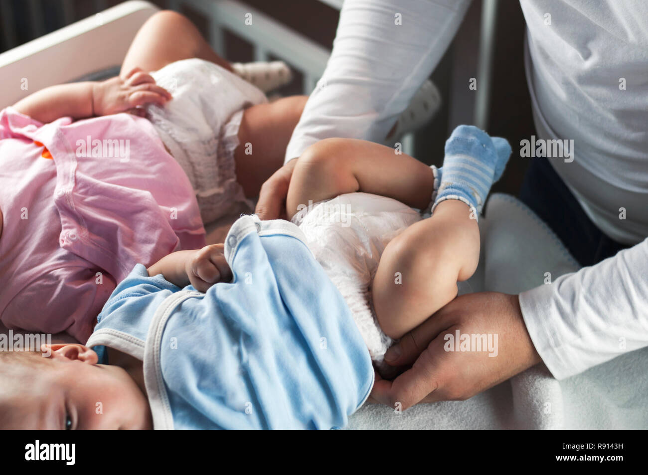 Los jóvenes papá de cambios de ropa y cambia sus pañales para sus hijos  pequeños gemelos, chico y chica. Enfoque selectivo Fotografía de stock -  Alamy
