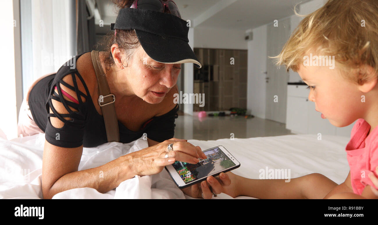 Abuela mostrando juego de smartphone al nieto Foto de stock