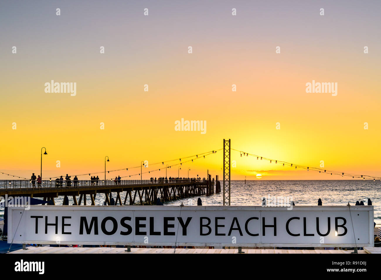 Adelaida, Australia del Sur - Marzo 11, 2018: El Moseley Beach Club cafe firmar vistos hacia el embarcadero, en una noche de verano Foto de stock
