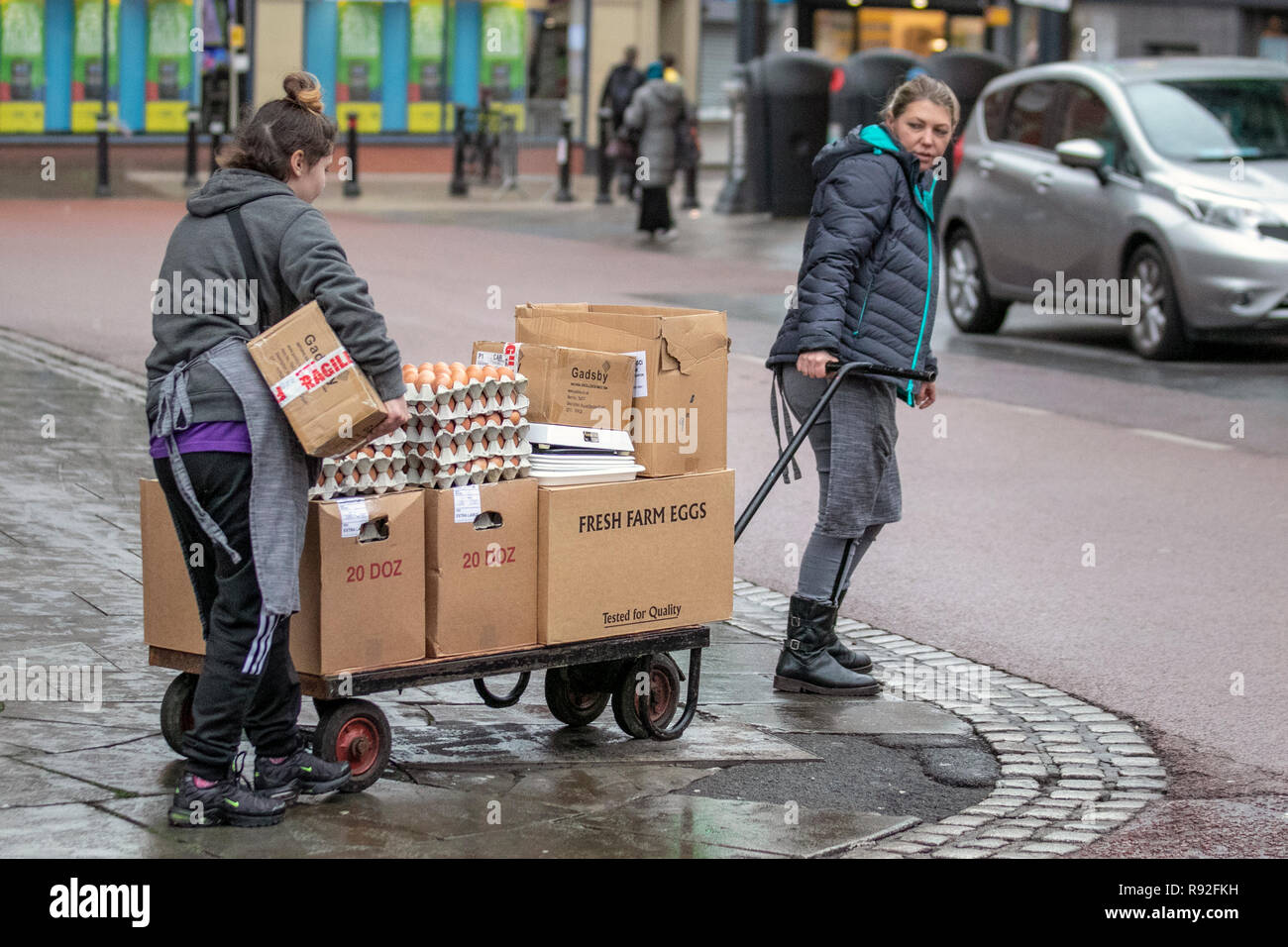 Preston, Lancashire, el clima del Reino Unido. El 18 de diciembre de 2018. Wet & día ventoso como mujeres entrega cajas de huevos grandes para el establecimiento hostelero en el centro de la ciudad. Crédito; MediaWorldImages/AlamyLiveNews Foto de stock