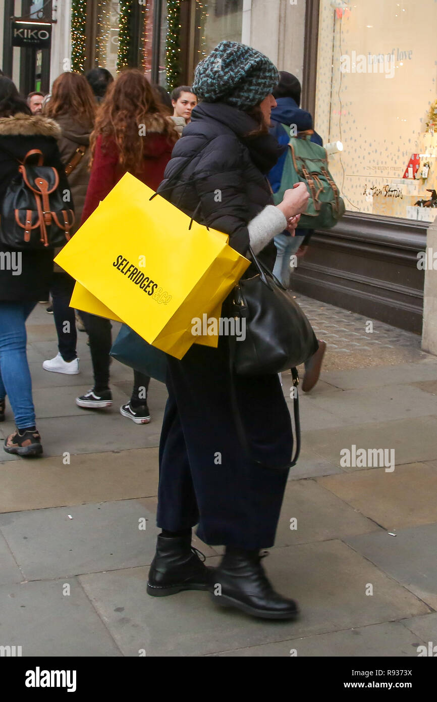 Una mujer es visto con bolsa de compras de Selfridges en la Oxford Street de Londres con 6 días para el día de Navidad. Los minoristas esperan una avalancha de compradores en el periodo previo a la Navidad como la venta en muchas tiendas han empezado. Foto de stock