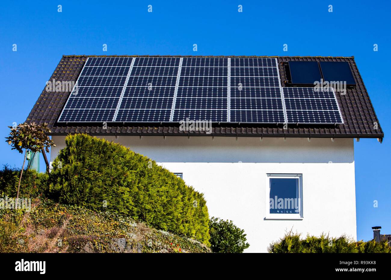 Techo de una casa residencial con paneles solares para generar electricidad y paneles solares térmicos para agua caliente Foto de stock