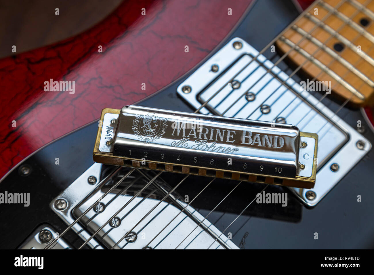 Banda Marina Hohner armónica en una vieja guitarra eléctrica. Blues, Rock, Música Foto de stock