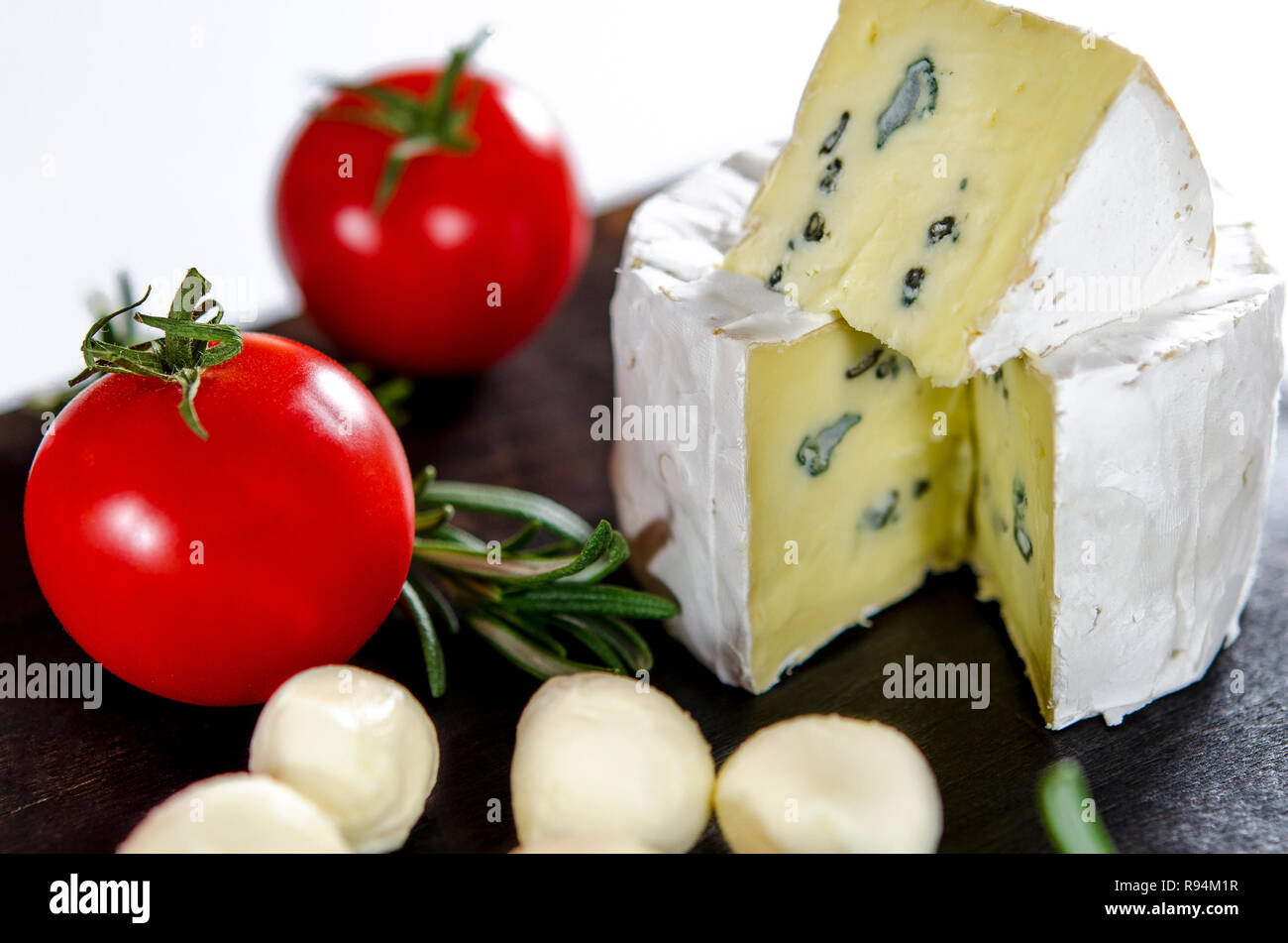 Surtido de quesos sobre la plancha de madera. El camembert, queso con moho  azul, mozzarella con tomates y Romero Fotografía de stock - Alamy