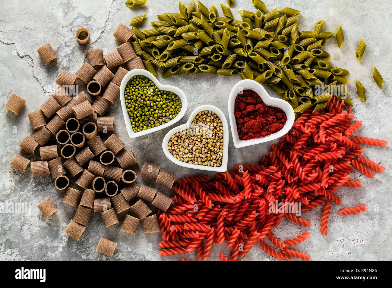 Las pastas sin gluten multicolor con ingredientes en cuencos en forma