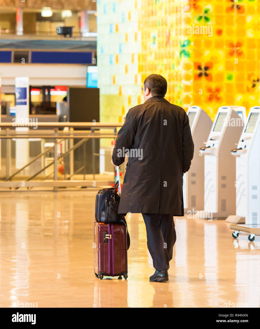 Tokio, Japón - 7 de noviembre de 2017: el hombre en un impermeable con una  maleta en el aeropuerto. Vista posterior. Con el enfoque selectivo  Fotografía de stock - Alamy