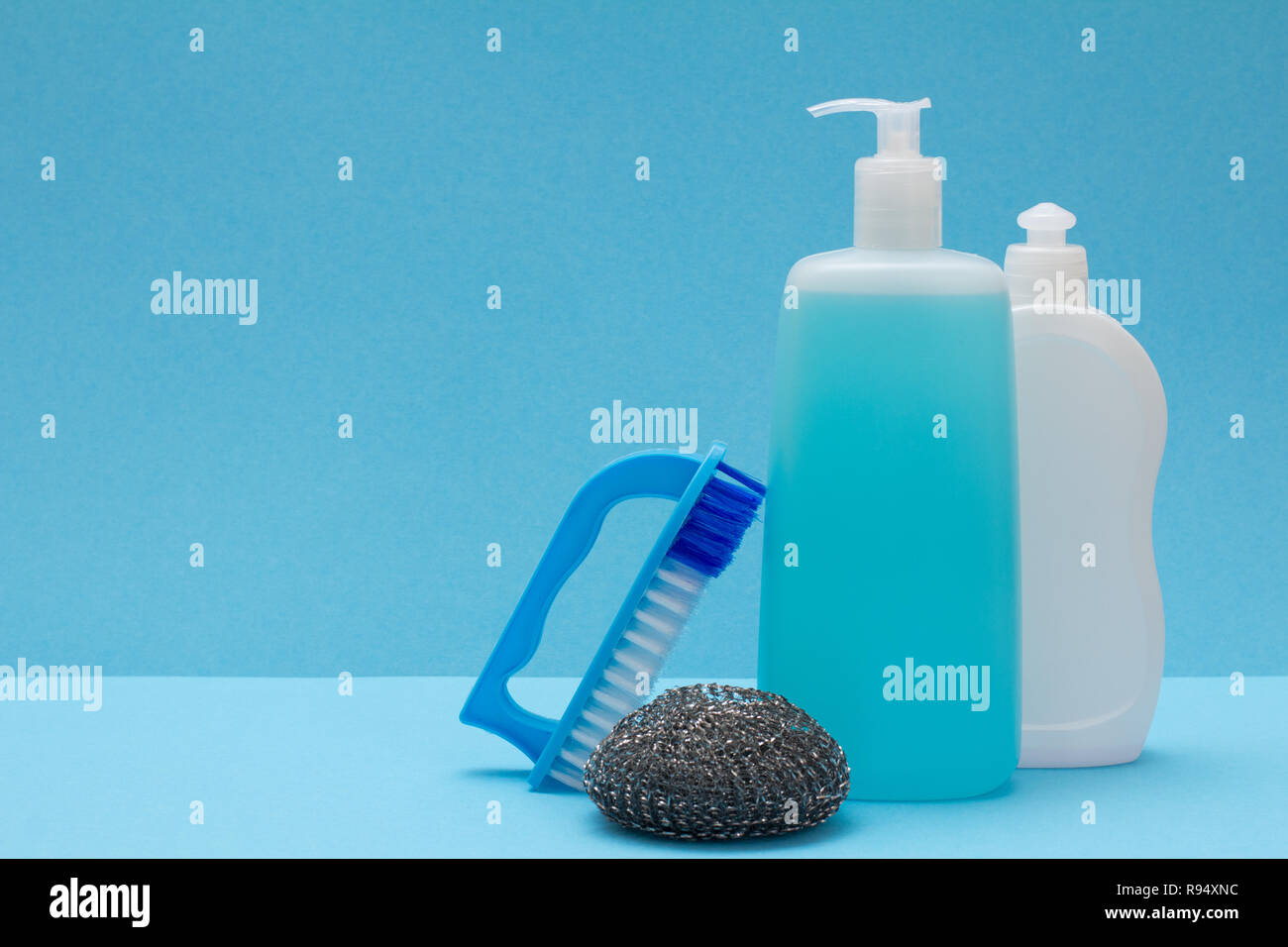 https://c8.alamy.com/compes/r94xnc/botellas-de-plastico-vidrio-y-detergente-limpiador-de-azulejos-cepillo-y-esponja-de-metal-sobre-fondo-azul-concepto-de-lavado-y-limpieza-r94xnc.jpg