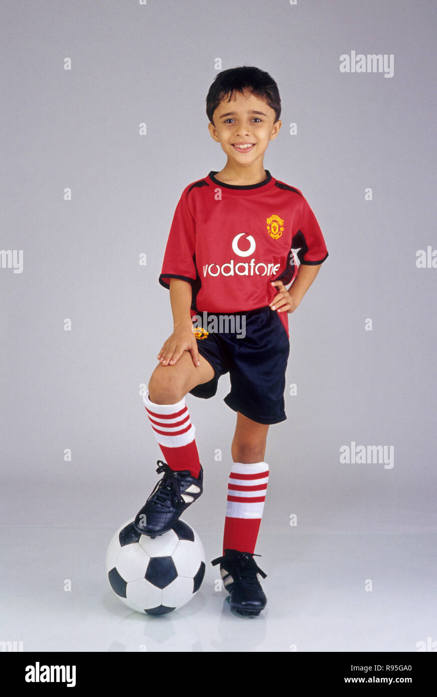 Niño vestido como jugador de fútbol, deporte usando pantalones cortos y una camiseta poner el sobre el balón de MR 496 Fotografía de stock - Alamy