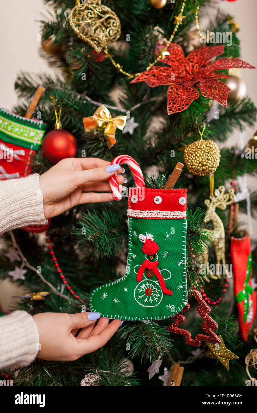 Mujer joven decorar el árbol de Navidad con bastones de caramelo y juguetes  en casa. Preparación para el año nuevo. Calcetines con dulces Fotografía de  stock - Alamy
