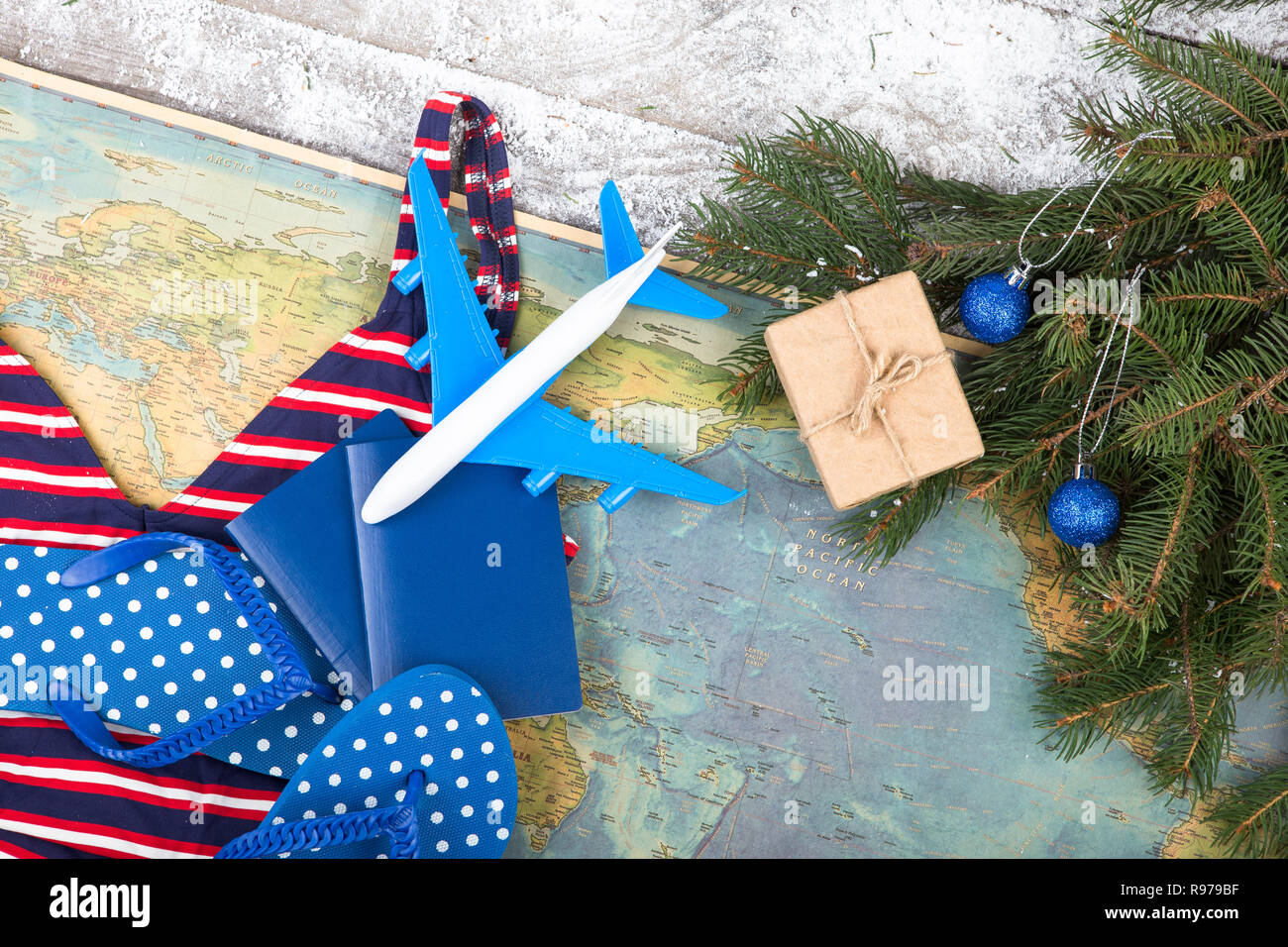 Concepto de Navidad - travel. Ramas de abeto con nieve, mapas, bañador,  pasaportes, caja de regalo, flops y avión de juguete Fotografía de stock -  Alamy