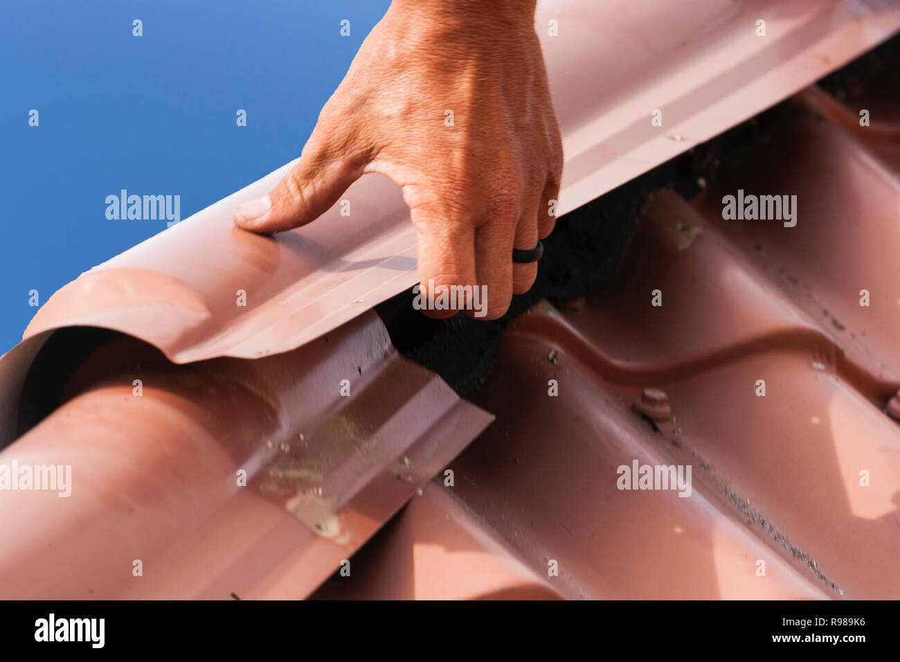 Hombre reparando techo metálico Foto de stock