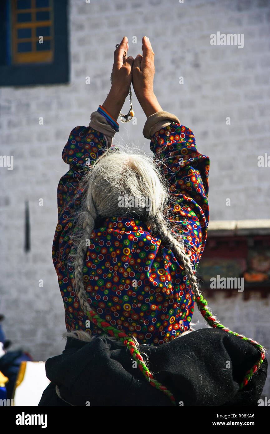 Lhasa, región autónoma del Tíbet, China : una vieja mujer tibetana reza fuera el Jokhang templo Barkhor Square. El Jokhang es considerado como el más Foto de stock
