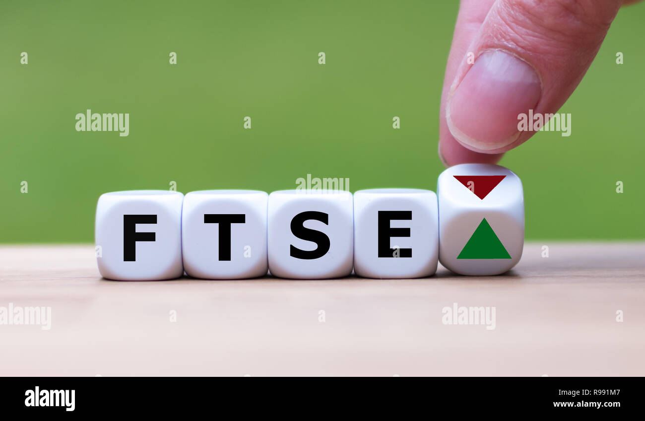 La mano es un giro dados y cambia la dirección de una flecha que simboliza que el FTSE 100 está cambiando la tendencia y sube en vez de bajar (o Foto de stock