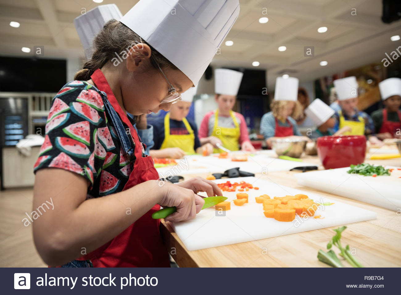 Chica centrada en clase de cocina cortar las zanahorias Foto de stock
