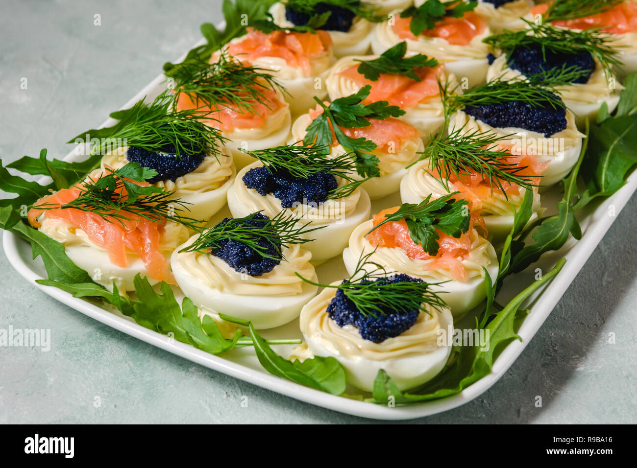 Huevos rellenos con salmón y caviar decorado con perejil y eneldo. Parte alimentos Foto de stock