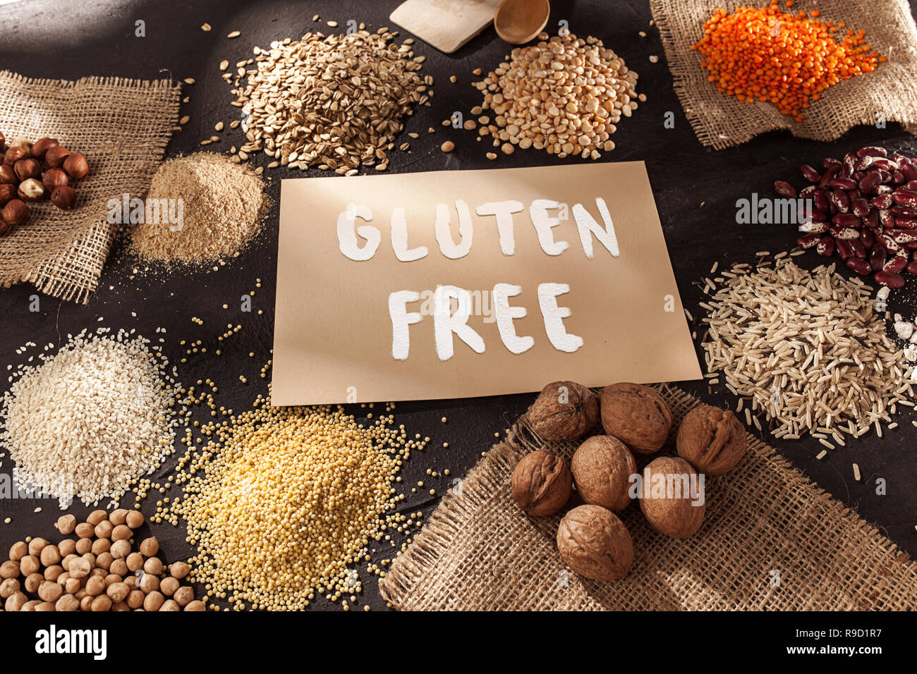 Harina y cereales sin gluten mijo, quinoa, pan de maíz, trigo sarraceno,  arroz marrón, pan y pastas con texto libre de gluten en idioma inglés con  una cuchara de madera, vista superior