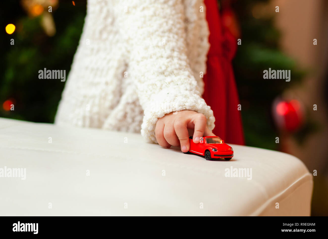 Hermoso pequeño niño juega con rojo pequeño coche de juguete. Foto de stock