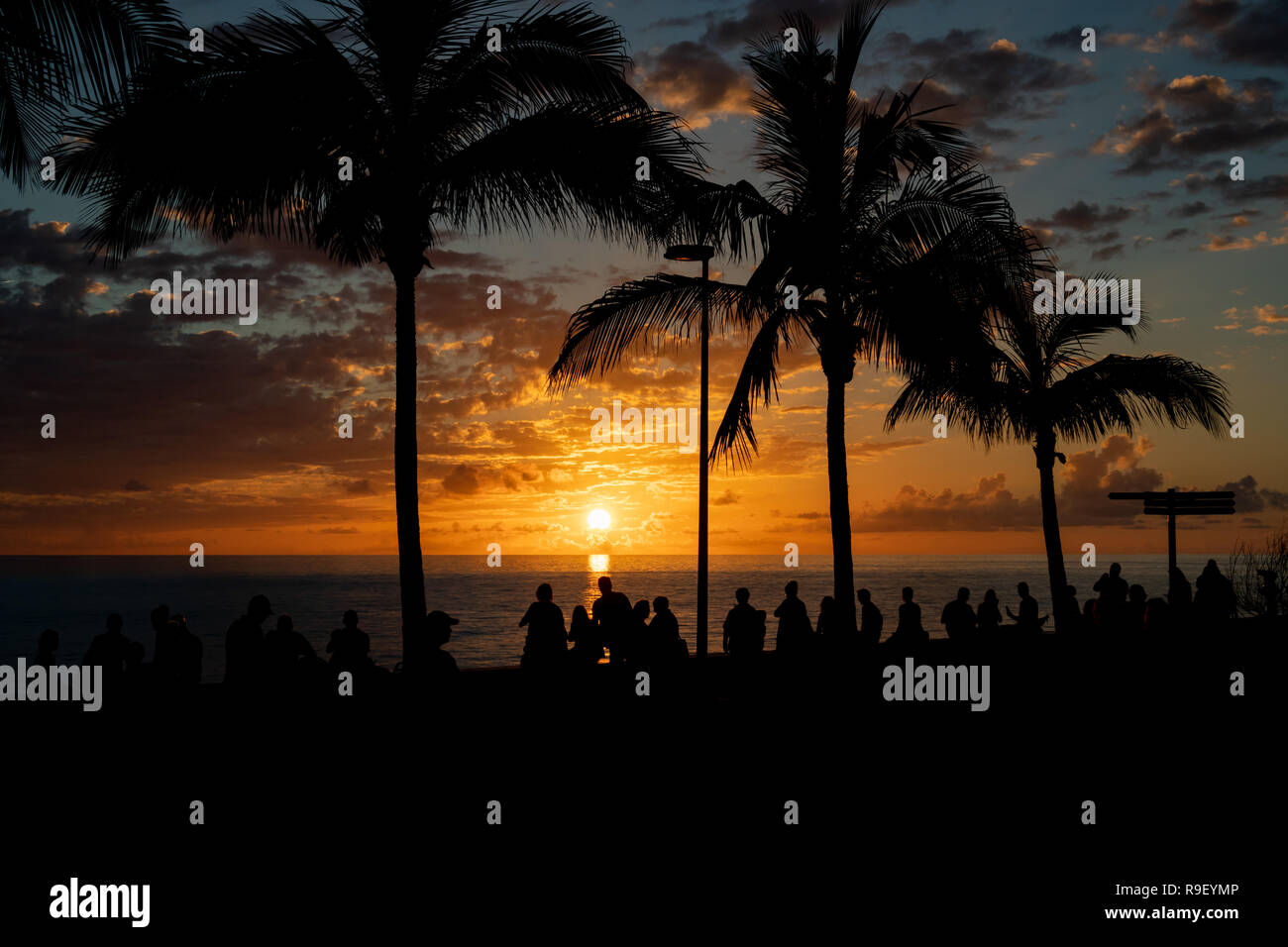 Silueta de las personas que se benefician de una hermosa puesta de sol sobre el mar abierto Foto de stock