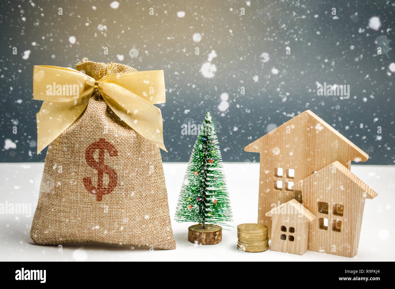 Casas de madera y árbol de Navidad y una bolsa de dinero. Navidad la venta  de propiedades inmobiliarias. Descuentos por compra de Año nuevo casa.  Comprar Apartamentos en baja Fotografía de stock -
