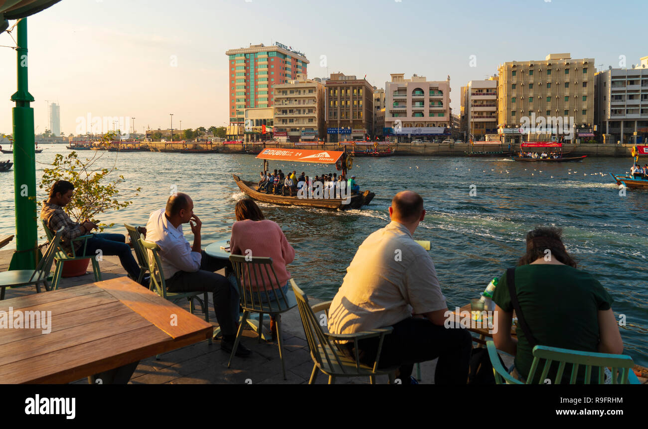 La gente en el café al lado del riachuelo al anochecer en la antigua Dubai, en los Emiratos Árabes Unidos. Foto de stock