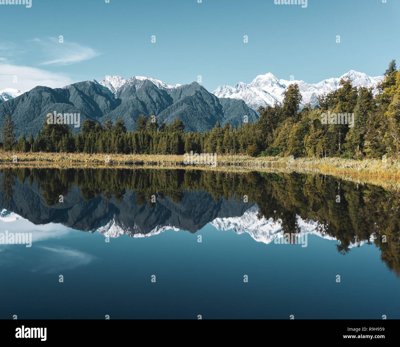El lago Matheson en la costa oeste de Nueva Zelanda actúa como un espejo en el cielo claro día Foto de stock