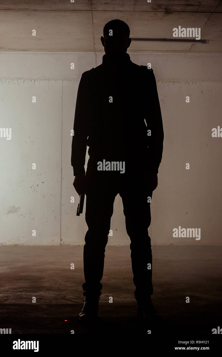 Silueta de un hombre parado con un revólver en sus manos Fotografía de