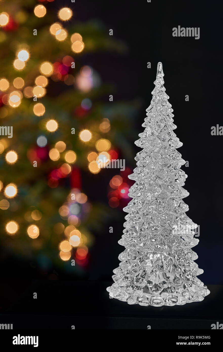 Árbol de navidad de cristal en la parte delantera de una verdadera navidad decorado con luces multicolores Foto de stock
