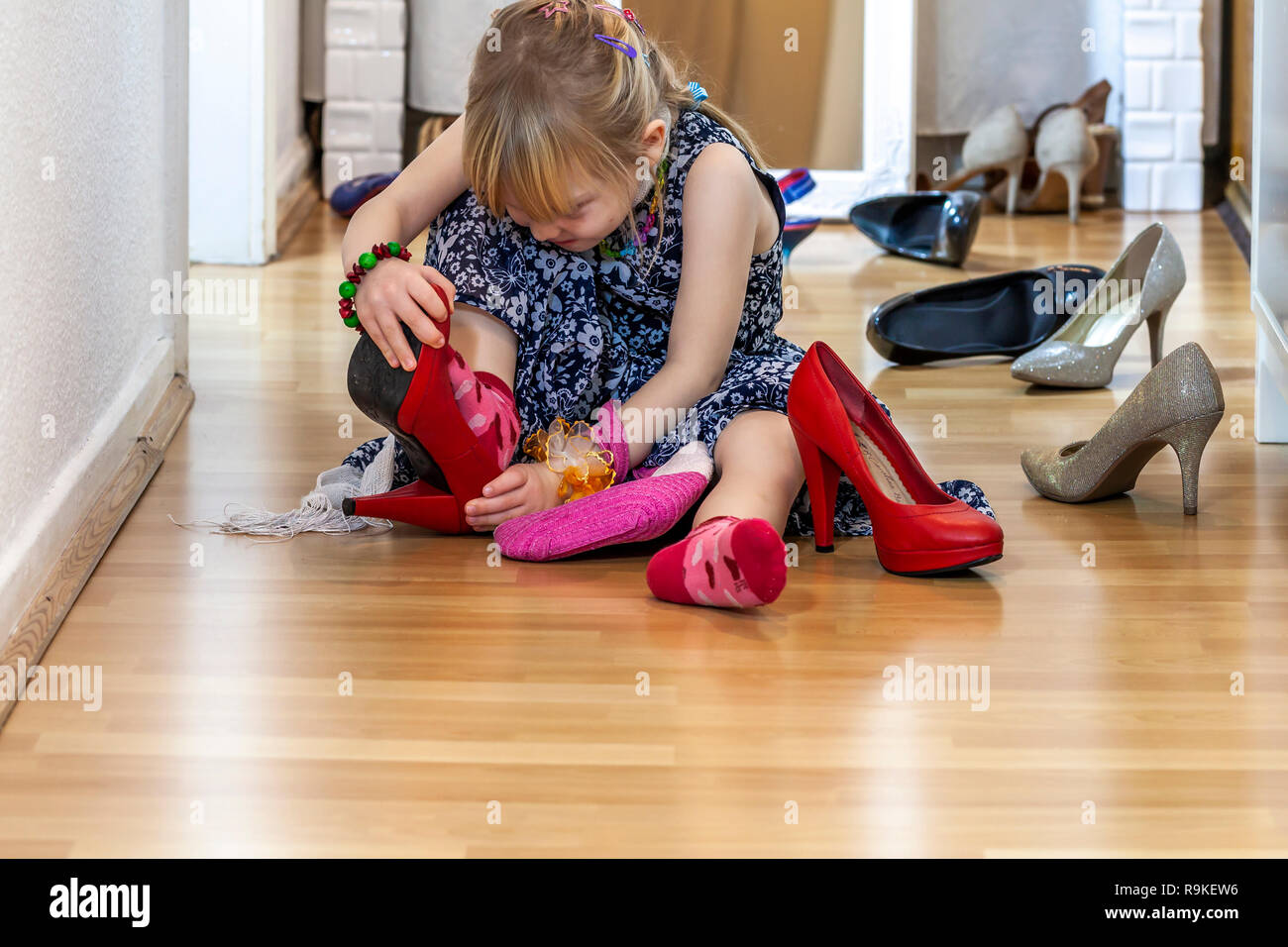La niña mide los zapatos de la madre con tacones: fotografía de