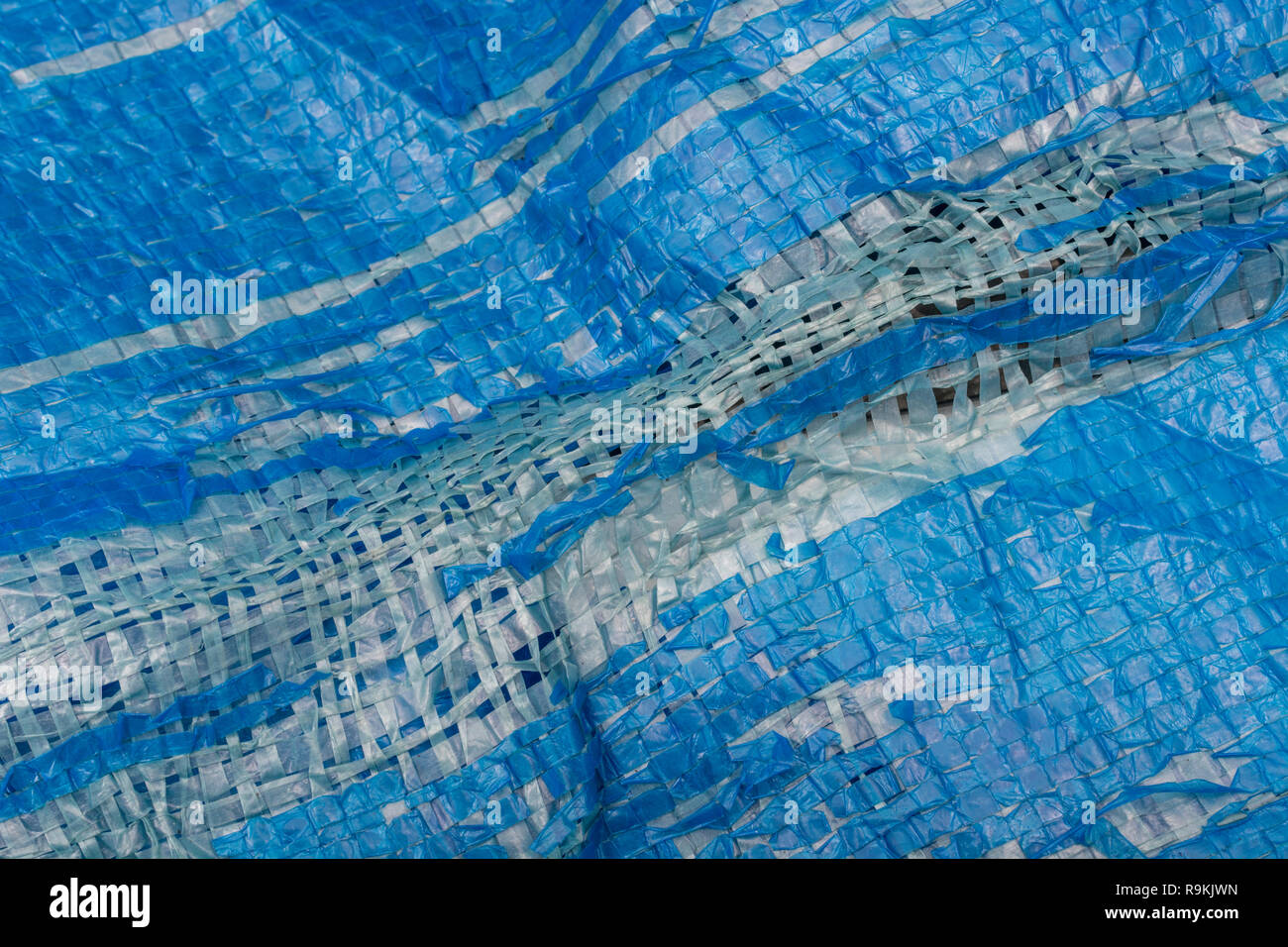 Macro-fotografía de muy desgastado azul Poly-Tarpaulin baratos - expuesto tejido interior de plástico laminado con tela azul / LDPE Polietileno de baja densidad. Foto de stock