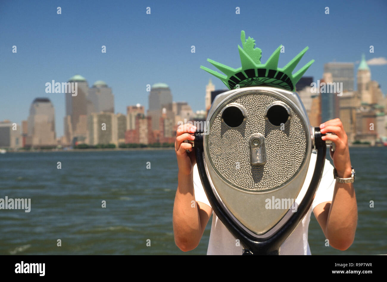 Turista adolescente vistiendo la libertad corona de espuma utiliza un visor con 2002 de la ciudad de Nueva York, en el fondo, en la ciudad de Nueva York, EE.UU. Foto de stock