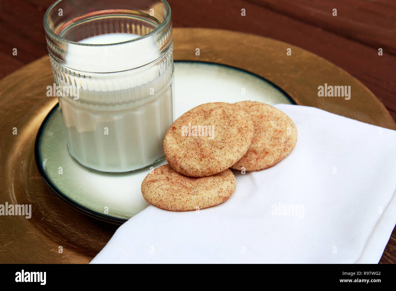 Cookies Snickerdoodle sobre placa dorada con un vaso de leche blanca. Foto de stock