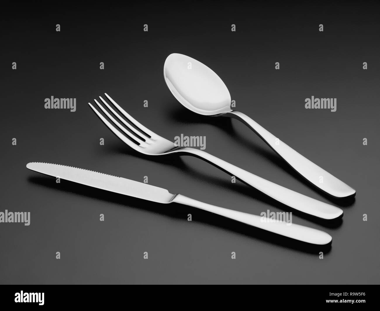 La cubertería de plata tenedor cuchara y cuchillo sobre negro Foto de stock