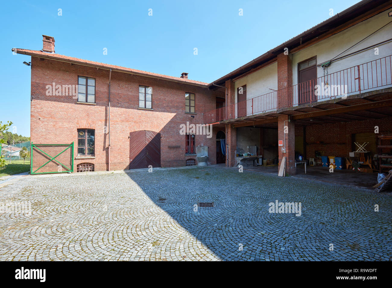 Antigua casa con patio, depósito y paredes de ladrillo en un día soleado de verano en Italia Foto de stock
