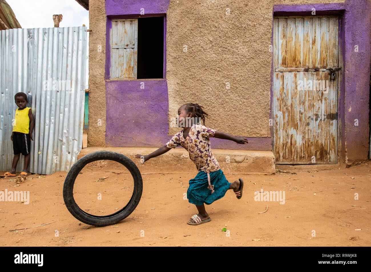 Chica improvisando jugar usando neumáticos de bicicletas en el mercado de Turmi, Etiopía Foto de stock