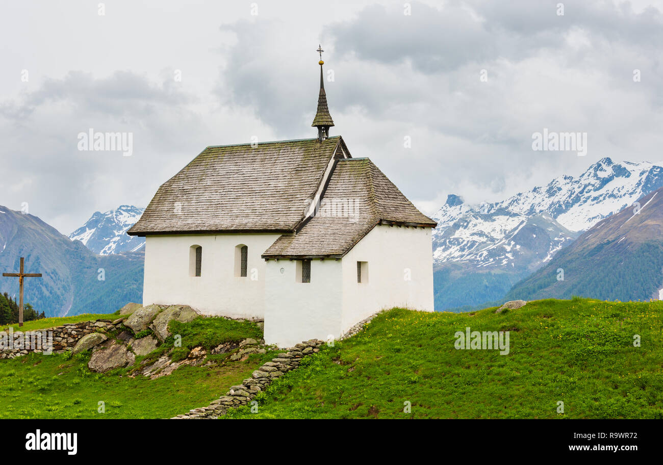 Bonita y pequeña iglesia antigua en Bettmeralp Alpes Mountain Village, Suiza. Vista nublada de verano. Foto de stock