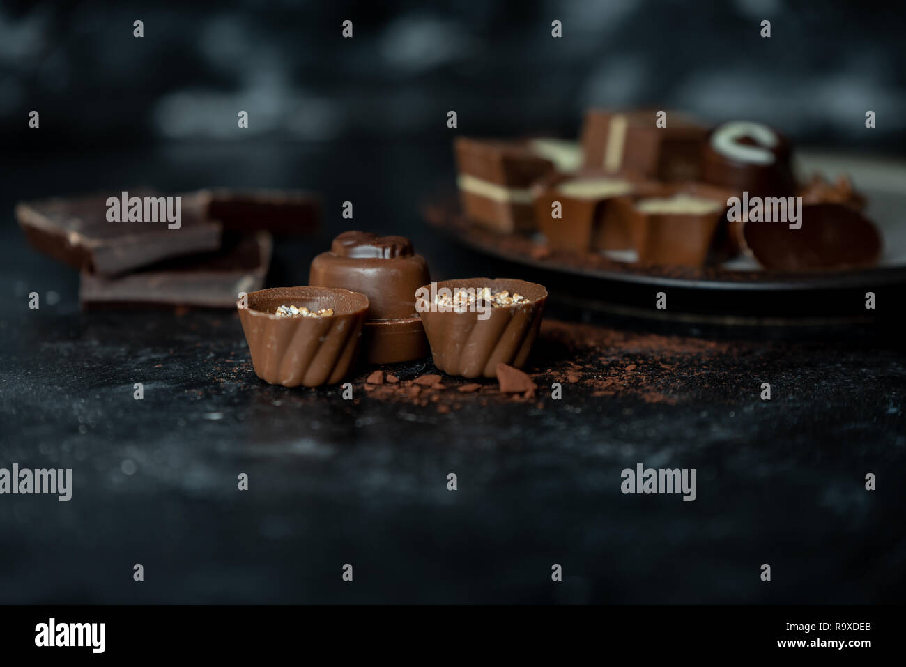 Diferentes pralines, dulce de leche, oscuro y chocolate blanco sobre un fondo oscuro, de madera Foto de stock