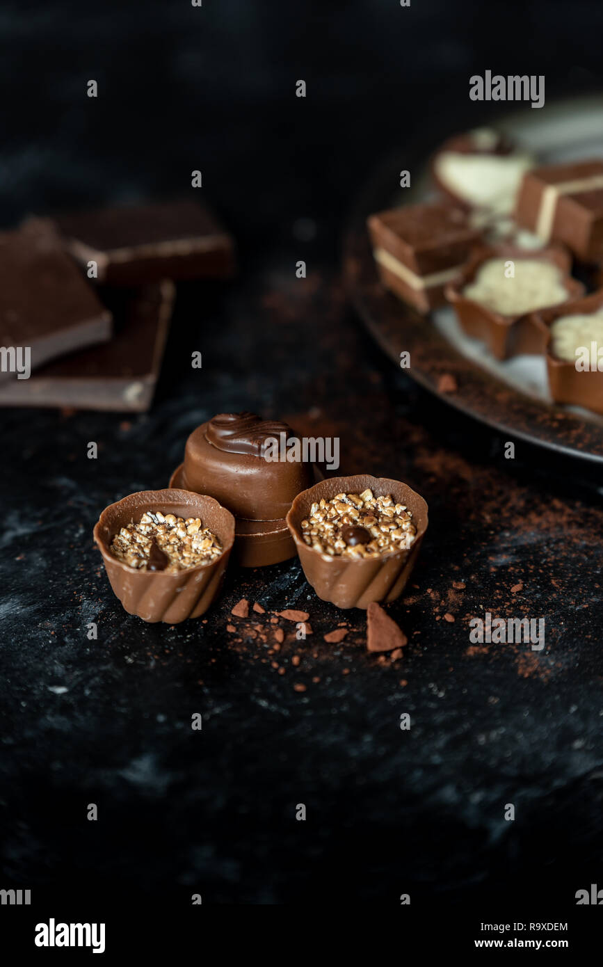 Diferentes pralines, dulce de leche, oscuro y chocolate blanco sobre un fondo oscuro, de madera Foto de stock