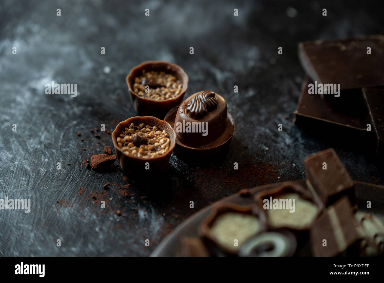 Diferentes pralines, dulce de leche, oscuro y chocolate blanco sobre un fondo oscuro, de madera Foto de stock
