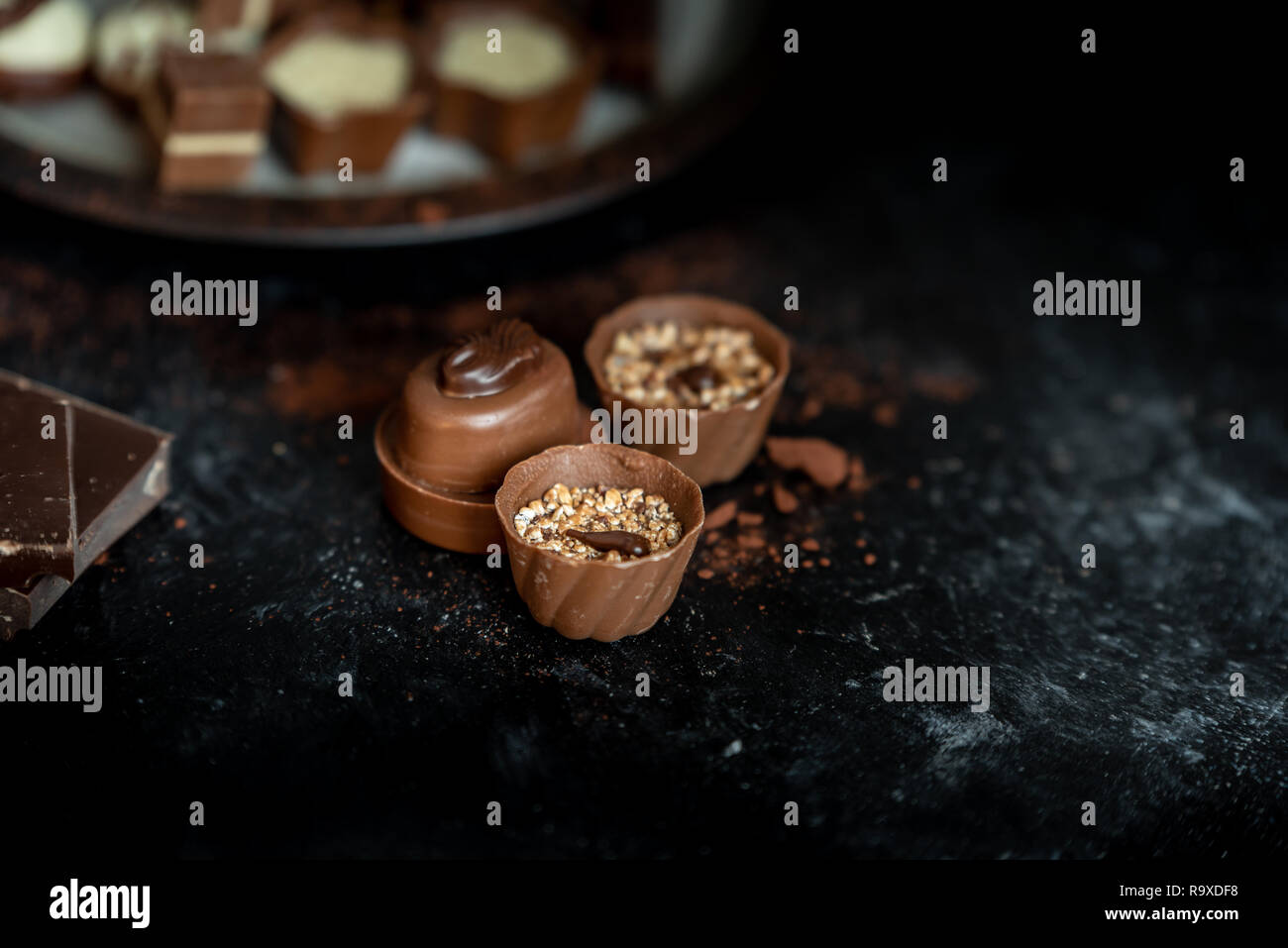 Diferentes pralines, dulce de leche, oscuro y chocolate blanco sobre un fondo oscuro, de madera Foto de stock