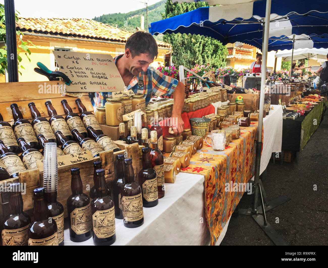 Los pueblos traen la cerveza local, la comida, el postre para la venta en el mercado de fin de semana de Moustiers-Sainte-Marie, Provence-Alpes-Côte d'Azur, Francia 6/23/2017 Foto de stock
