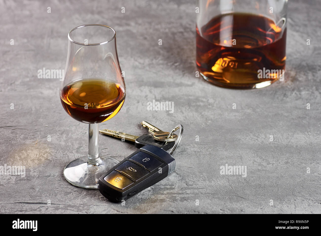 Vidrio y botella de whisky en una mesa de piedra y las llaves del coche. Conducción en la embriaguez Foto de stock