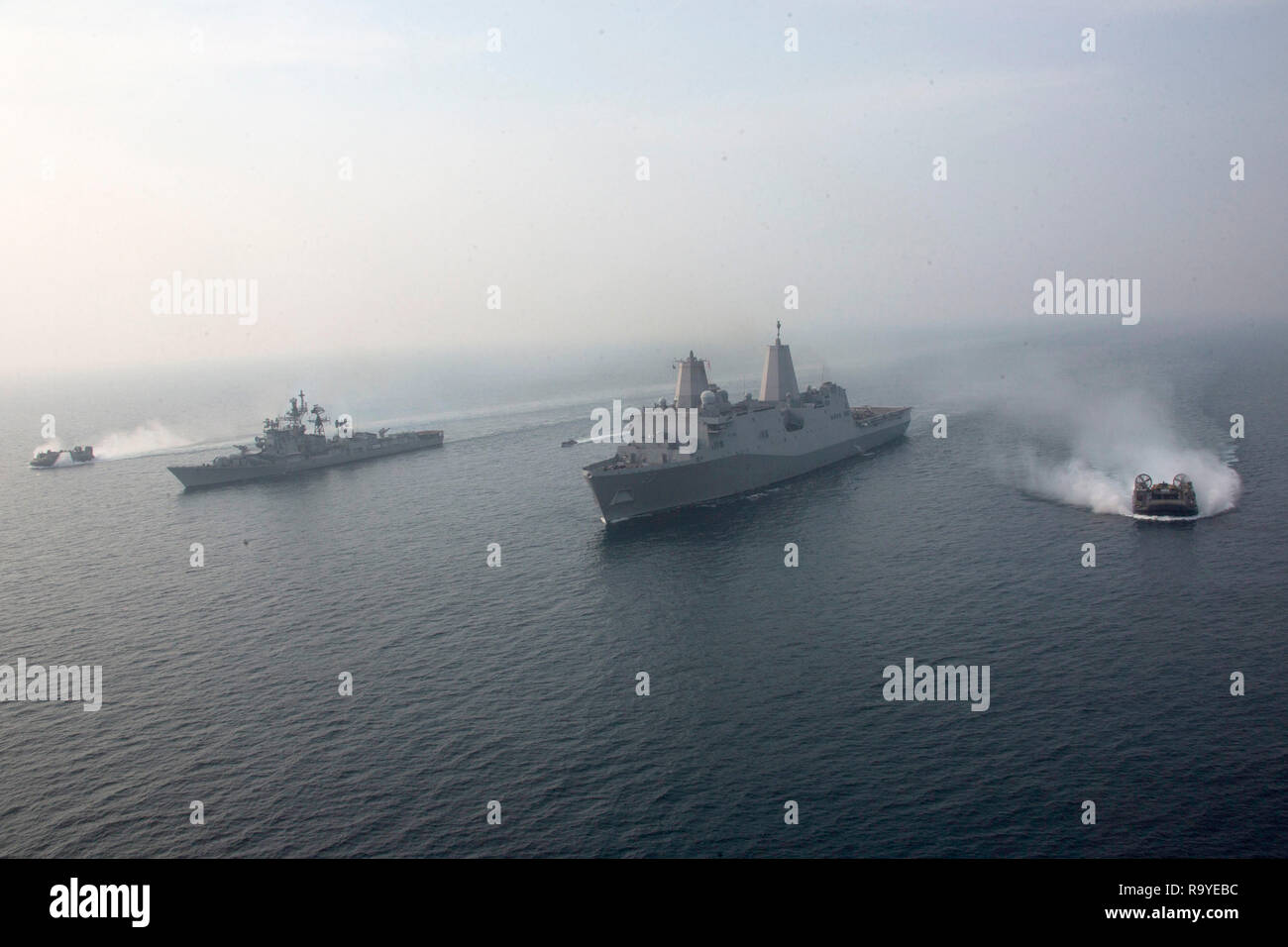 Desembarco de la Marina de EE.UU., cojín de aire, maniobras junto a la Marina de los EE.UU. San Antonio clase dock buque anfibio de transporte USS Anchorage, centro, y el destructor de la Marina india INS Rajput, izquierda, durante ejercicios de cooperación el 26 de diciembre de 2018 en el Océano Índico. Foto de stock