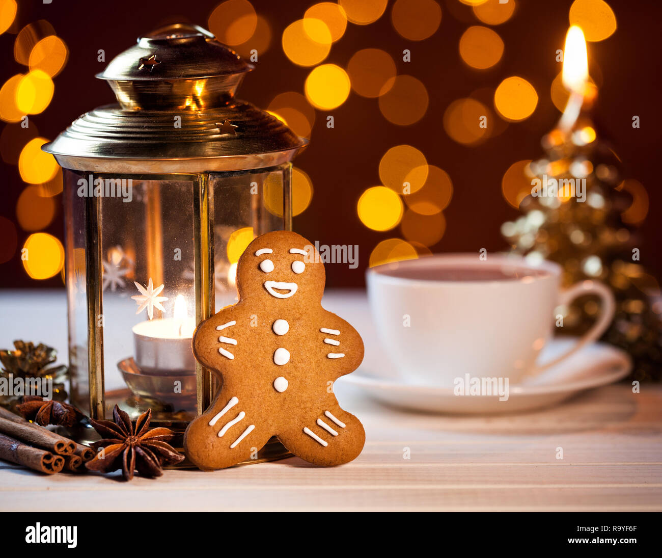 Gingerbread cerca de linterna, las especies y la taza de café a bokeh de fondo amarillo Foto de stock