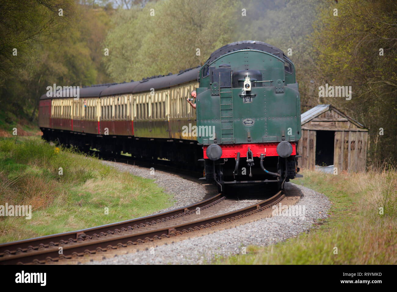 Un tren de vapor con tierna tira un conjunto de carruajes antiguos en retroceso como es la escasez de puntos de inflexión en el North Yorkshire Moors Railway. Foto de stock