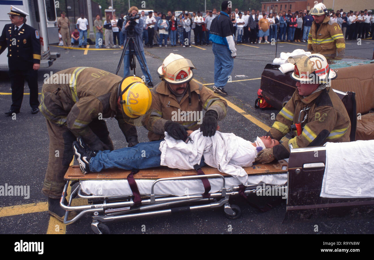 Los bomberos trabajan en una mujer herida herida en un auto accidente Foto de stock
