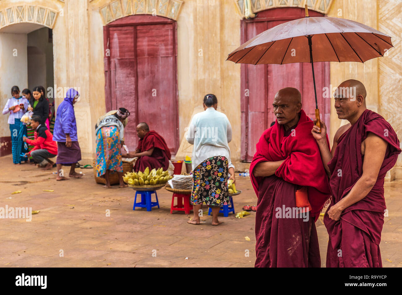 Dos monjes bajo un paraguas en el interior de un templo en myanmar Foto de stock