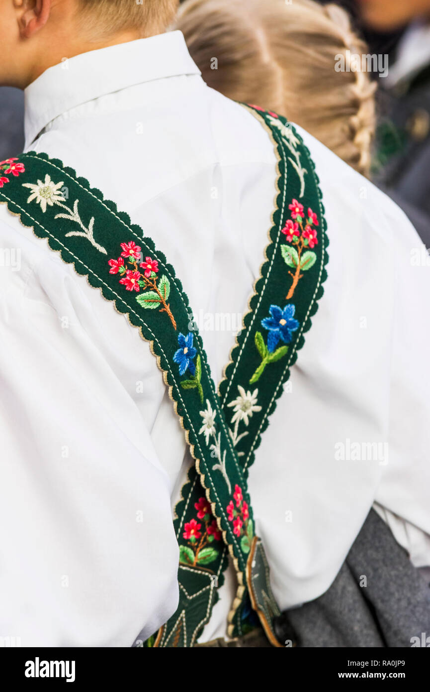 Joven vistiendo ropa tradicional con tirantes bordados mostrando getian rodamiento y edelweiss Foto de stock